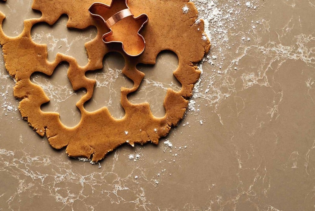 brown counter with cookie dough being cut into gingerbread men